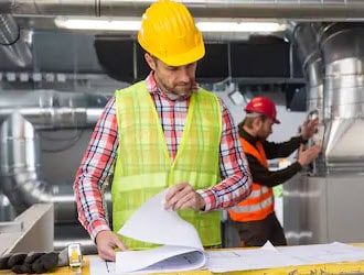 Construction workers reviewing blueprints indoors.